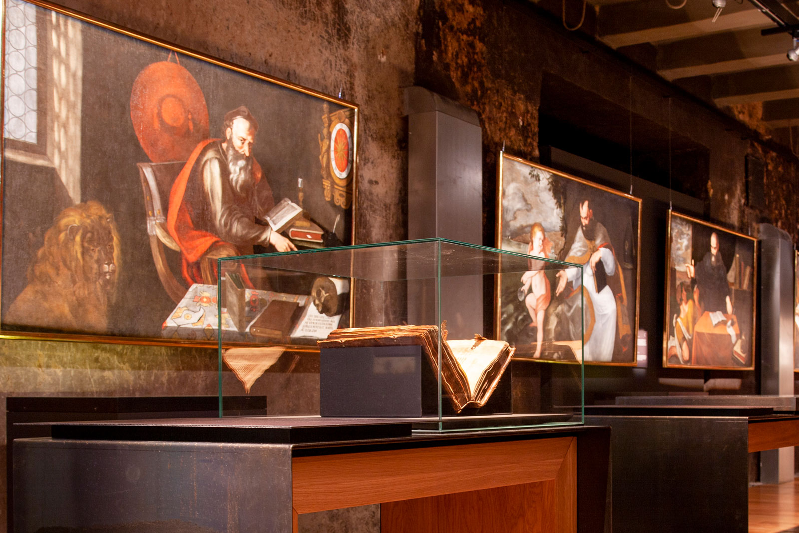 Das Referenzbild für Ausstellungsgestaltung aus der Sonderausstellung „Macht des Wortes“ zeigt eine Gemäldegalerie mit Exponatpräsentation in Vitrinenhauben.