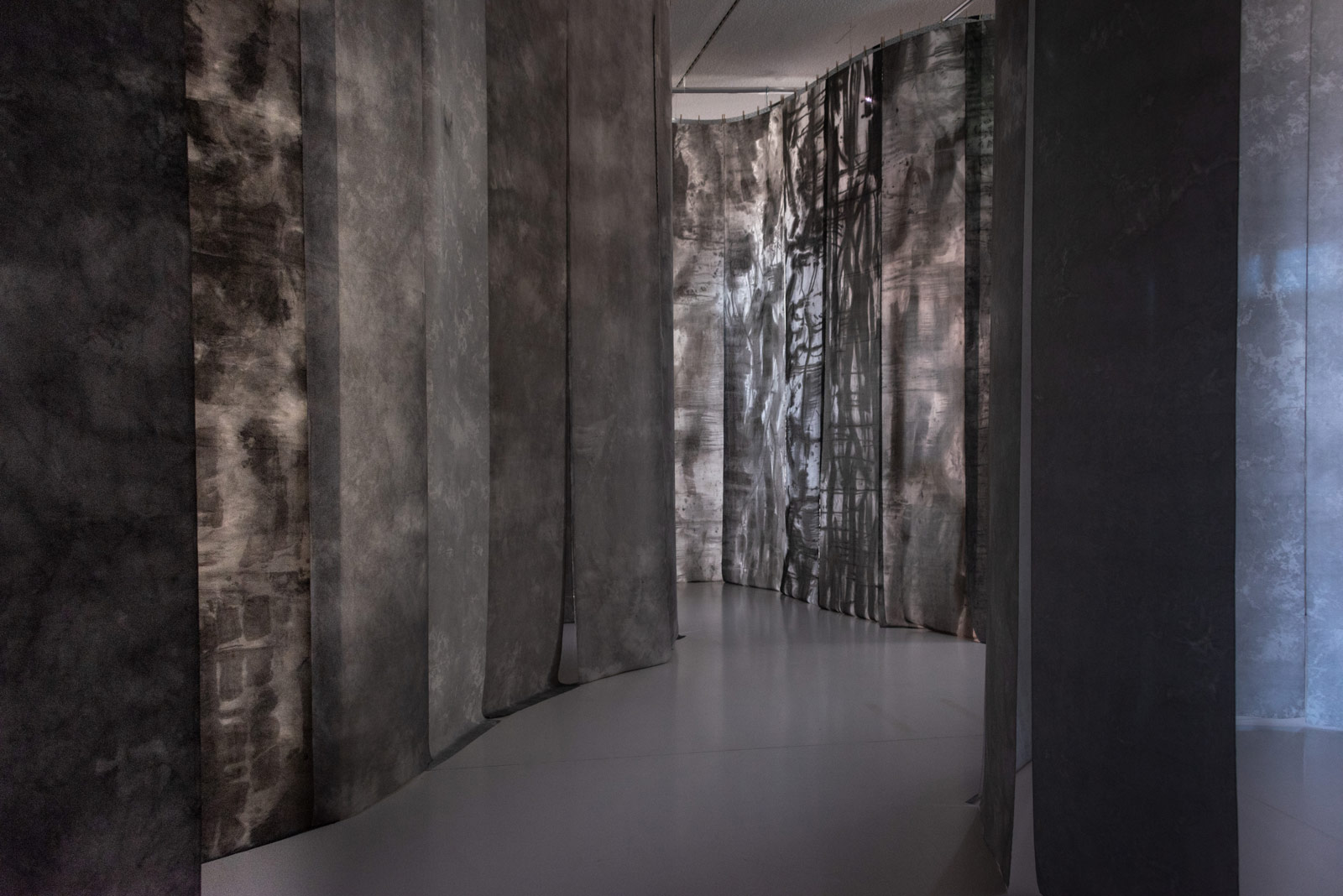 Das Referenzbild für Ausstellungsgestaltung aus der Sonderausstellung No intention: Koho Mori-Newton zeigt eine Rauminszenierung mit Textildruck und Lichtgestaltung.