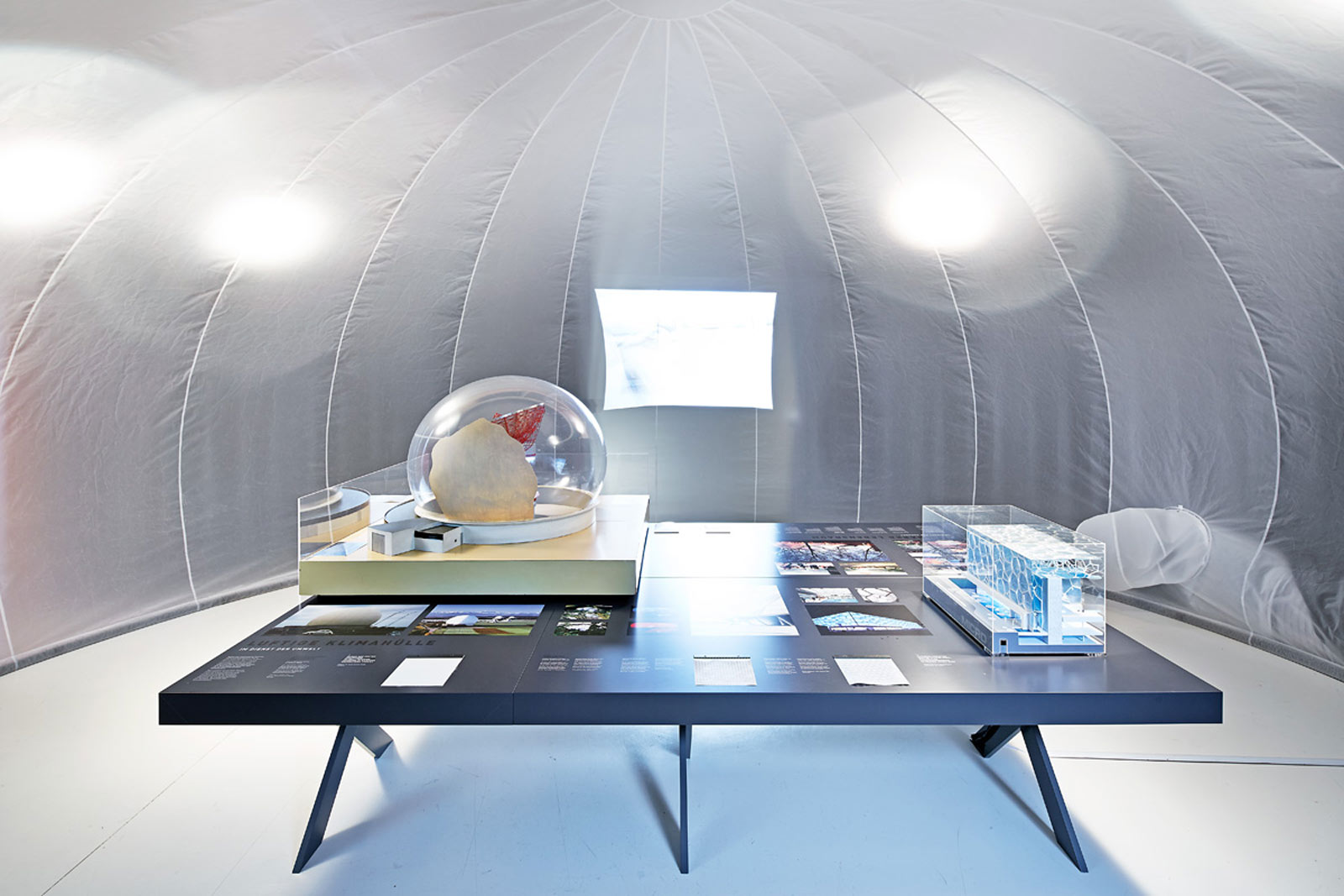 Das Referenzbild für Ausstellungsgestaltung aus der Sonderausstellung „Textile Architektur“ zeigt eine Medienstation mit einer Projektion der Allianz Arena.