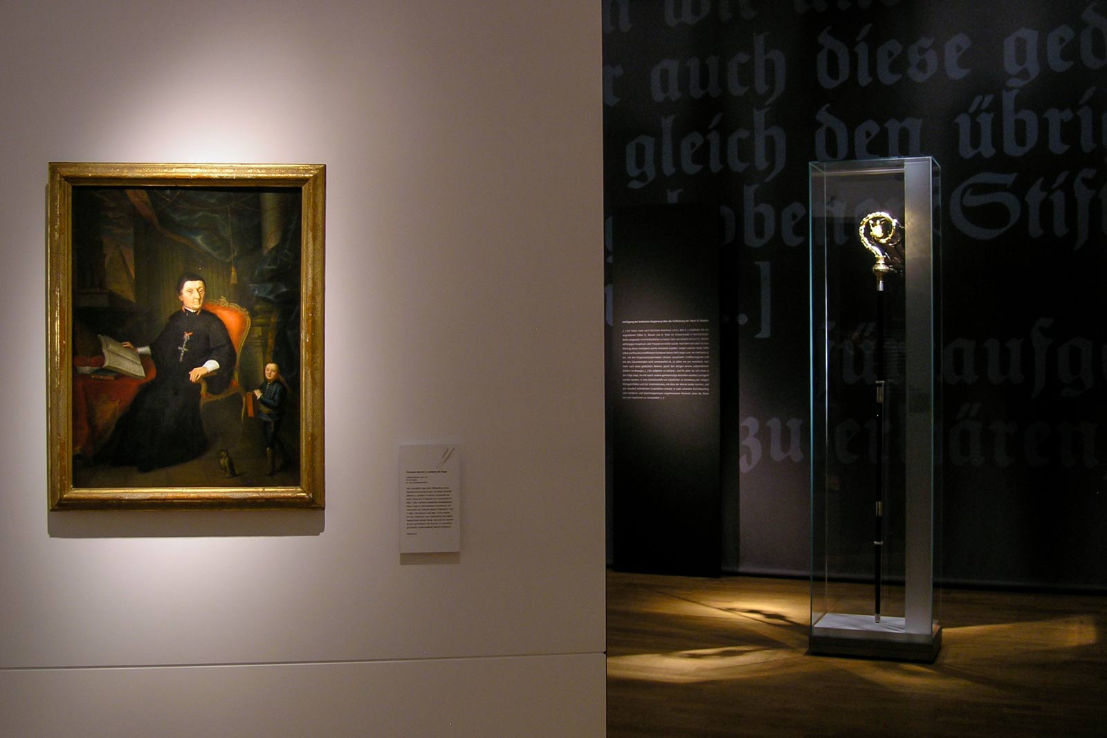 Das Referenzbild für Ausstellungsgestaltung aus der Sonderausstellung „Macht des Wortes“ zeigt eine Rauminszenierung mit Exponatlicht.