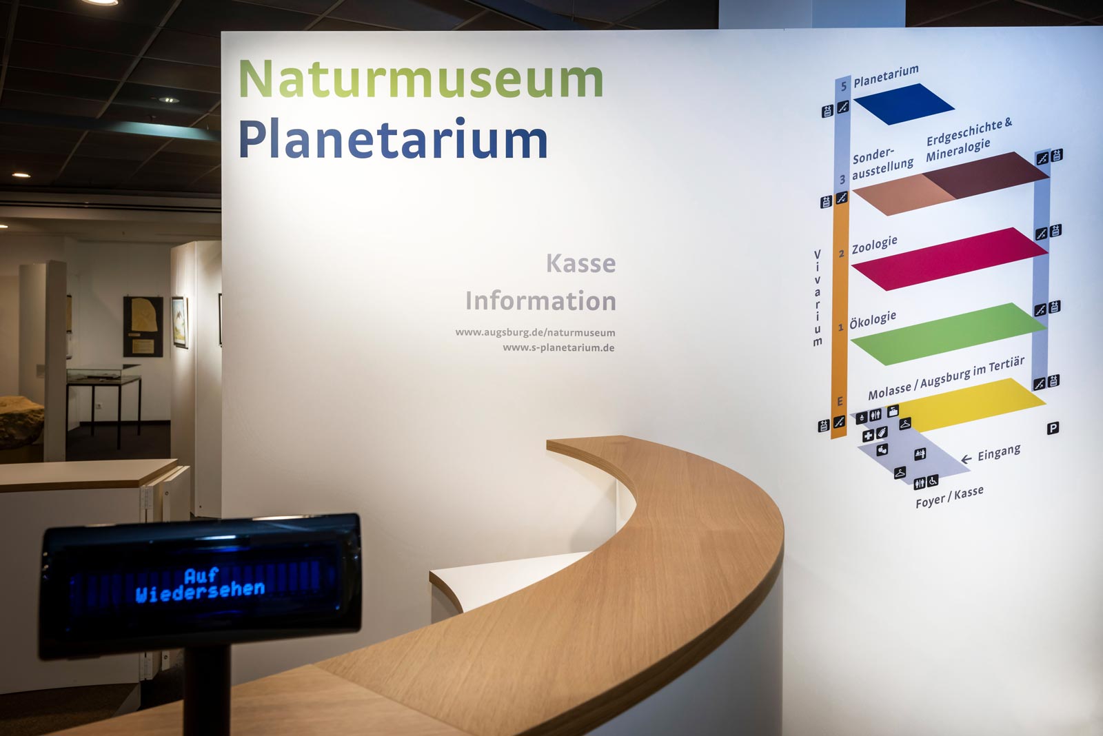 Das Referenzbild für die Innenarchitektur des Foyers im Naturmuseum Augsburg zeigt das Leitsystem und die Kasse.