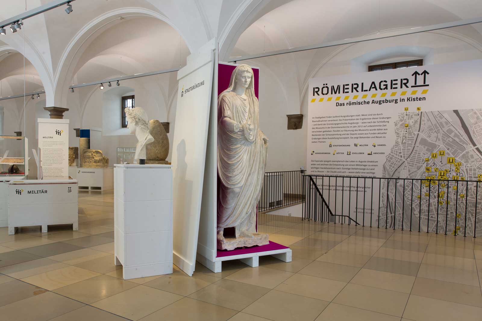 Das Referenzbild für Ausstellungsgestaltung aus der Interimsausstellung „Römerlager – Das Römische Augsburg in Kisten“ zeigt ein Leitsystem.
