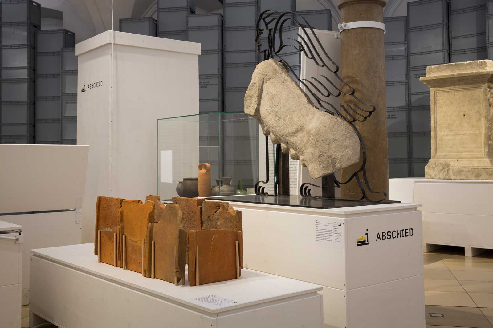 Das Referenzbild für Ausstellungsgestaltung aus der Interimsausstellung „Römerlager – Das Römische Augsburg in Kisten“ zeigt eine Exponatpräsentation in Vitrinen.